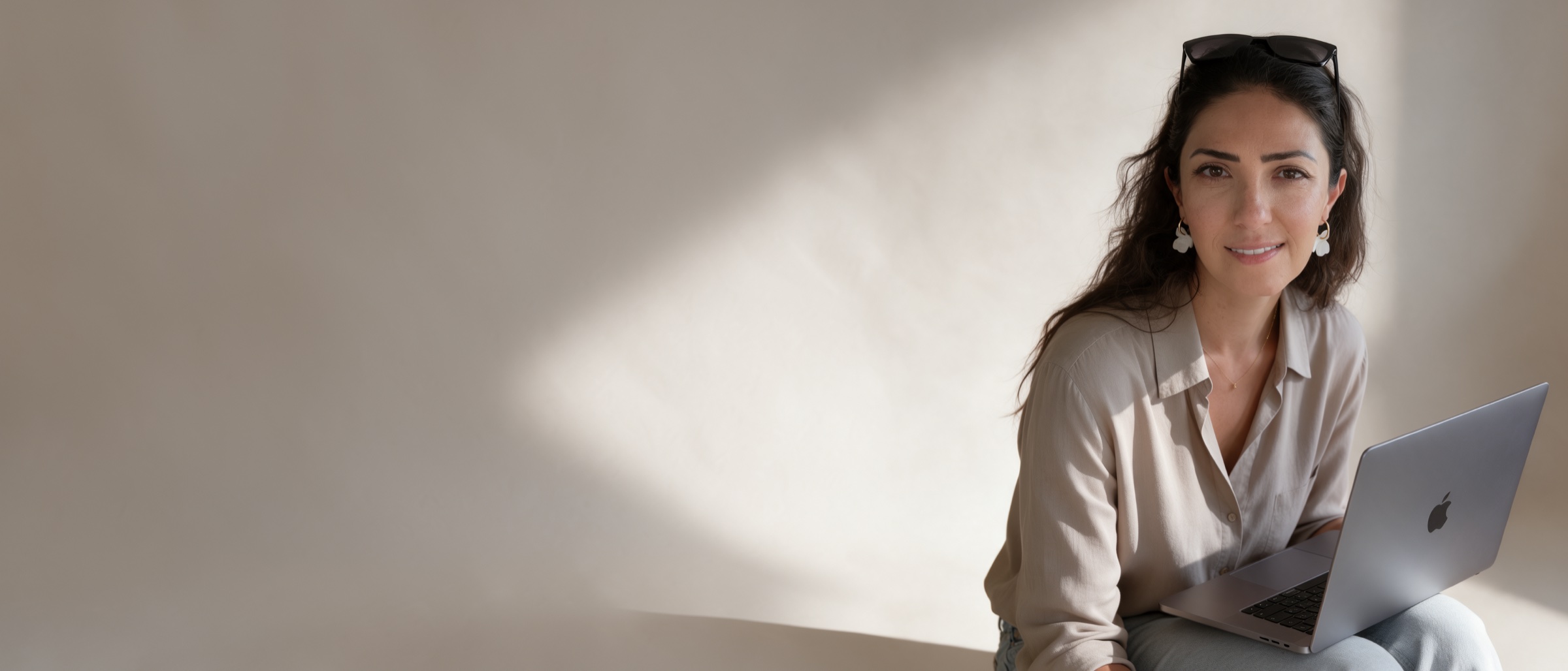Aline Haladjian, founder of Thorianne, with a laptop against a plaster wall