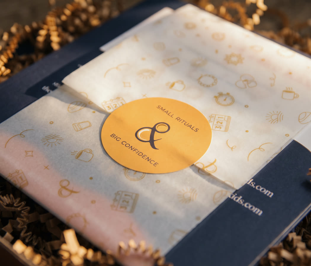 Close on the box seal, the ampersand and both lines of the lockup, sitting on the printed vellum