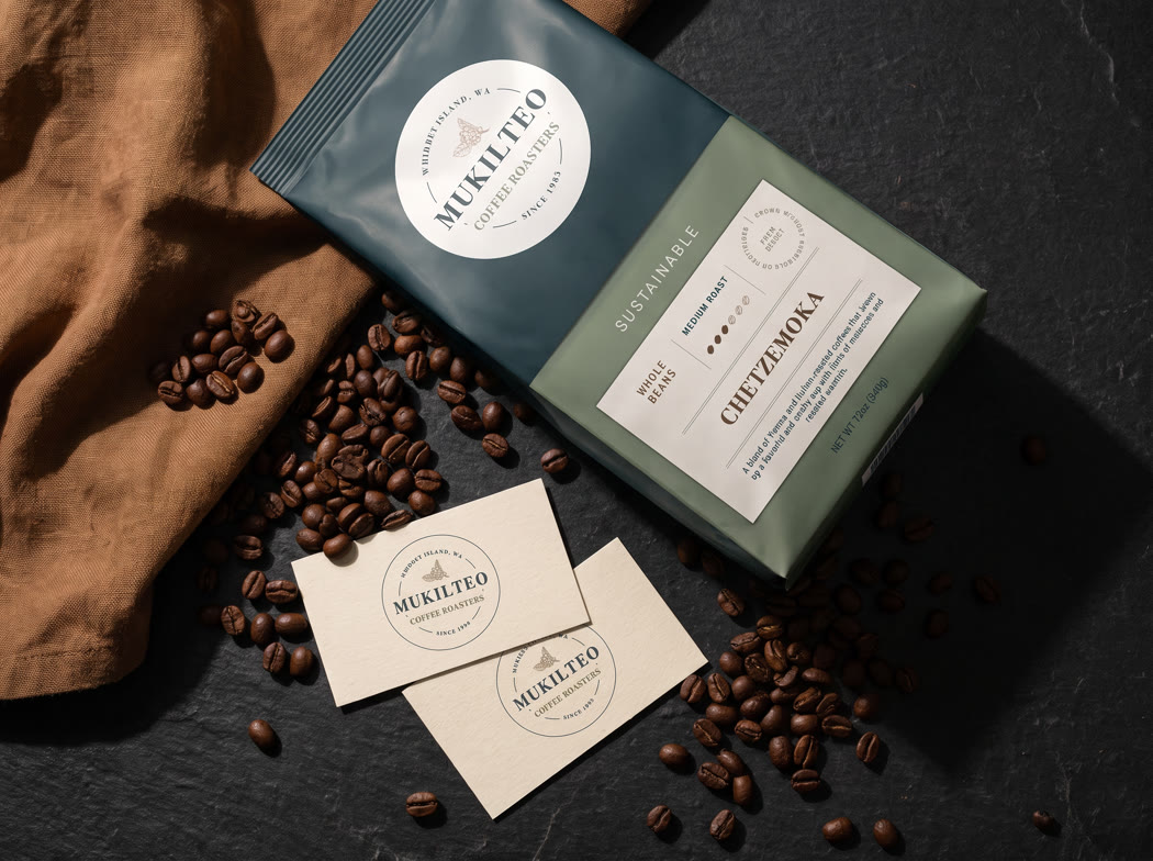 The coffee bag with business cards and loose beans on a dark counter