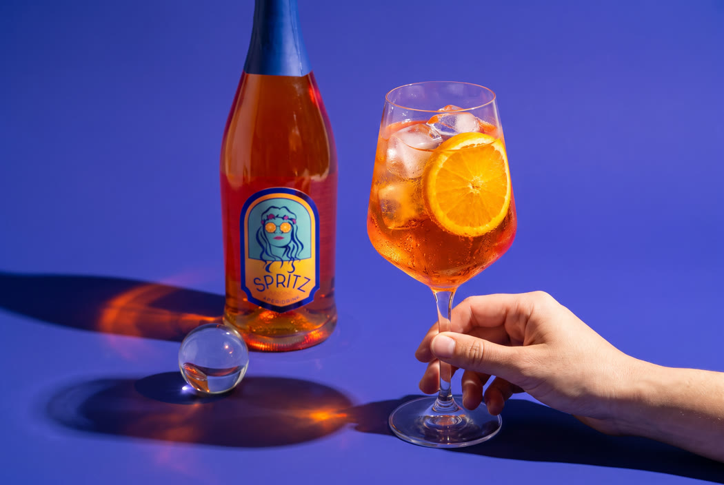 A poured glass with ice and orange, the bottle behind it