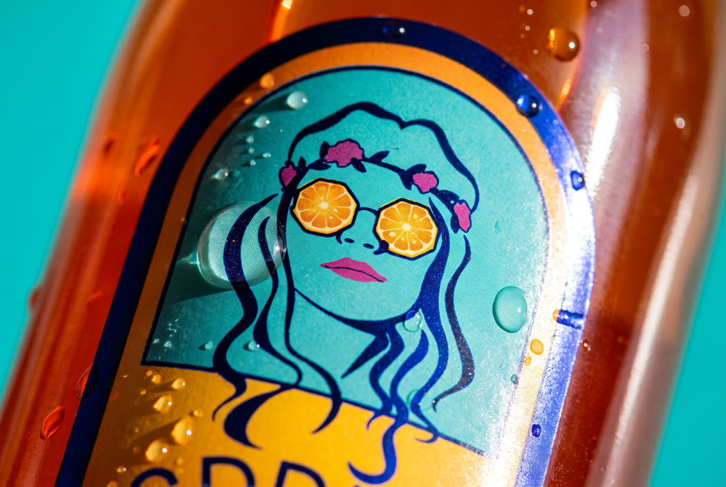 Close on the illustrated face and the orange slice lenses, wrapping the curve of the glass