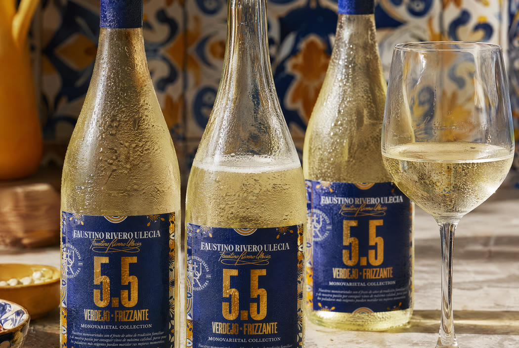 Three bottles on a stone counter against the same blue and yellow tile the label border is drawn from